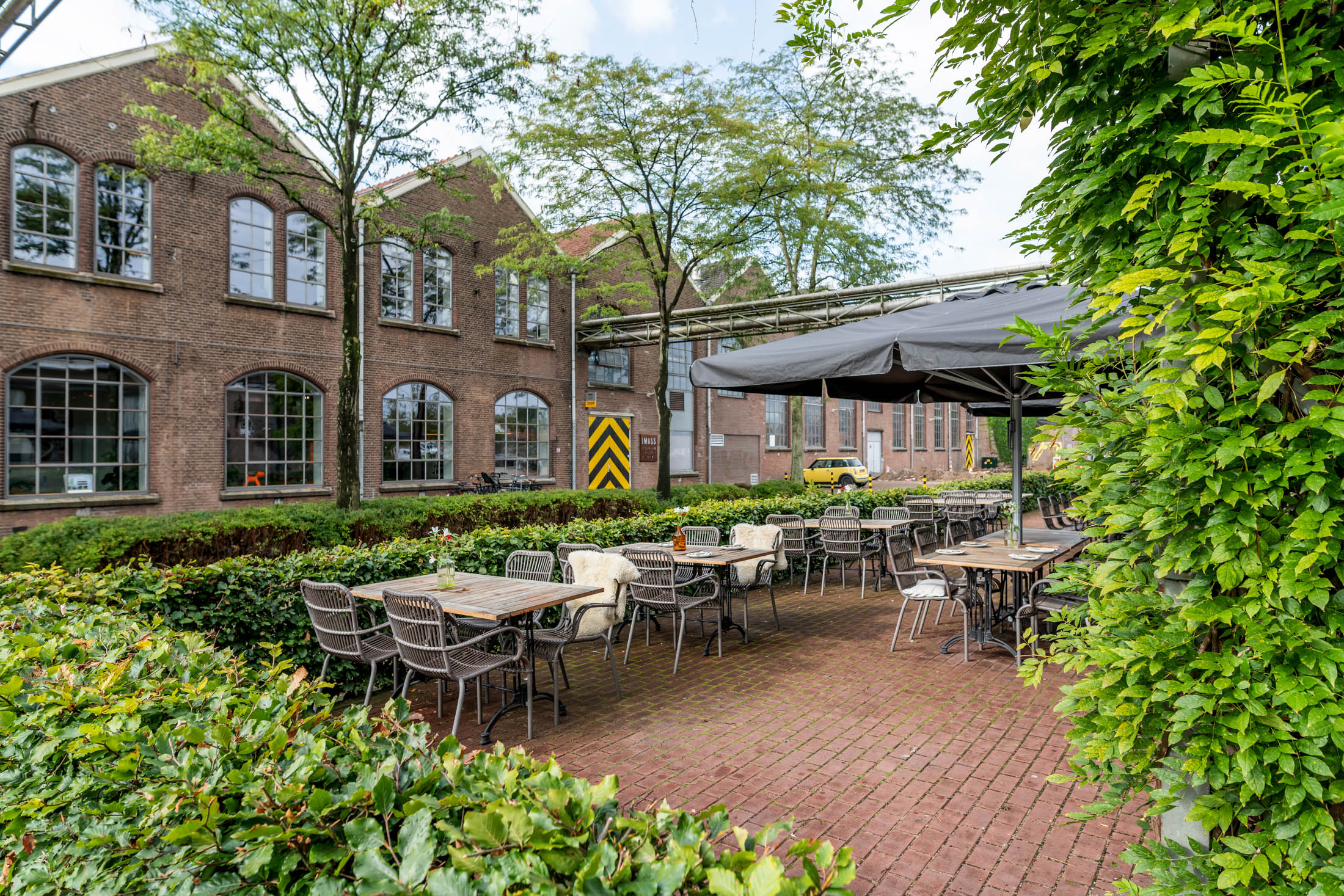 Groen terras van trouw- en evenementenlocatie Centraal Ketelhuis op de Wagenwerkplaats in Amersfoort met zitplaatsen en industriële gebouwen op de achtergrond