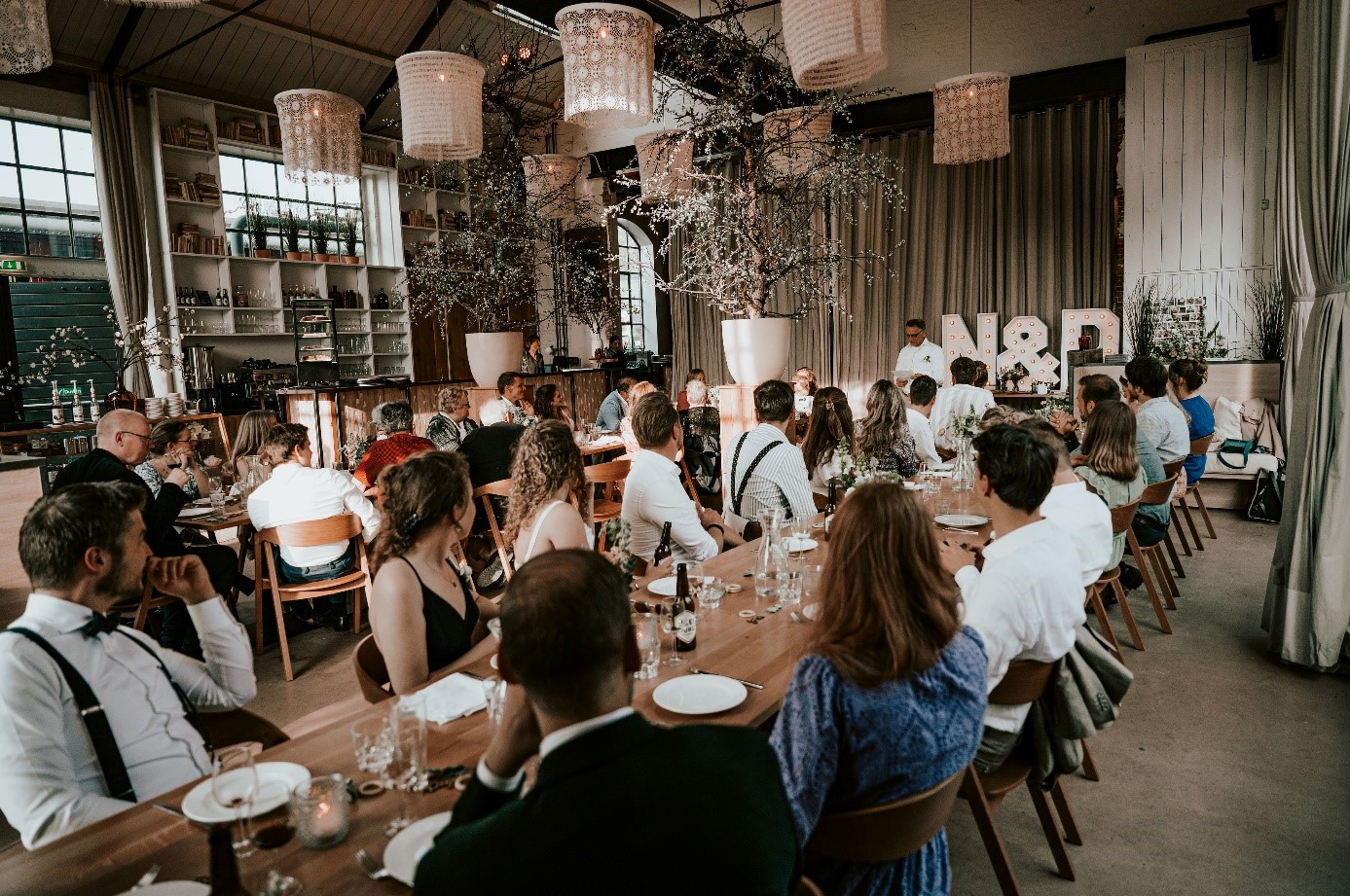 Gasten genieten van een gezamenlijk diner aan lange tafels in de industriële setting van het Centraal Ketelhuis in Amersfoort